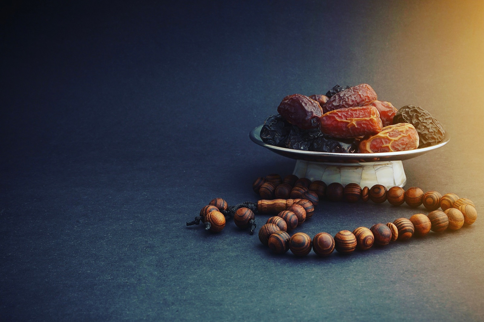 Dattes et chapelet en bois sur fond sombre, symboles du Ramadan