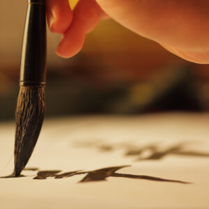 Main tenant un pinceau pour écrire une calligraphie arabe